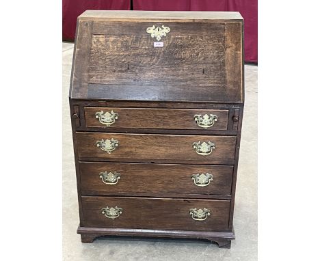 An antique oak bureau with fitted interior over four long drawers, raised on bracket feet. 18th century and later. 28½" wide