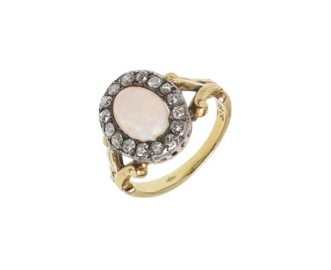 the oval-shaped solid white opal is set within a surround of old-cut diamonds, with fleur de lys set shoulders, in 18ct gold,