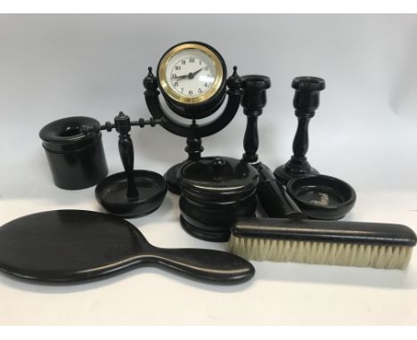 A ebonized dressing table set including clock candle sticks mirror, brush tidy jar ring tree .