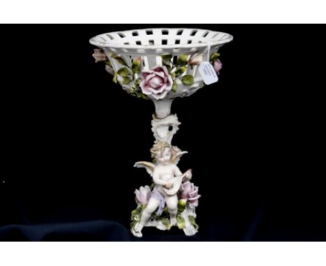A Continental figural comport with applied roses to the basket bowl, below, is a cherub playing a lute, 35cm high