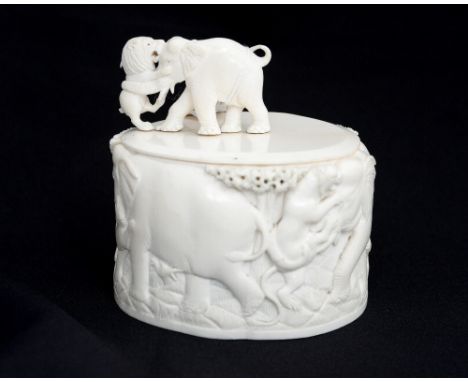 A late 19th century carved ivory box and cover, decorated in the round with a scene of lions attacking elephants, the finial 