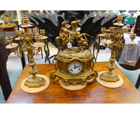 A late Victorian early Edwardian gilt brass German mantle clock with Hunter figure above dial with two matching candelabras, 