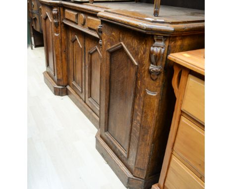 An early Victorian oak sideboard, of inverted breakfront form, the ends with doors enclosing sliding shelves, the central sec