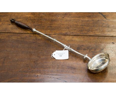 A white metal toddy ladle, the bowl inset with a silver coin, having a wooden turned handle 