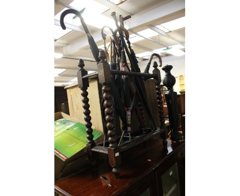 A late Victorian oak stick stand, with bobbin turned supports, complete with various sticks