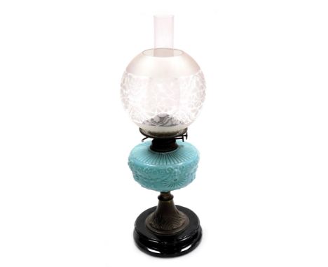 An early 20thC oil lamp, with an opaque shade decorated with flowers, an amber glass central reservoir on a cast iron base, w