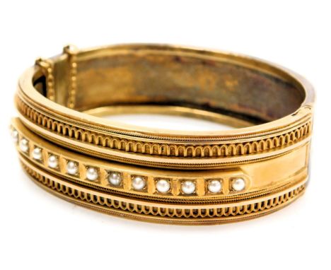 Victorian Etruscan Revival seed pearl set bangle, yellow metal, on a snap clasp, with safety chain as fitted, cased, 28.8g.