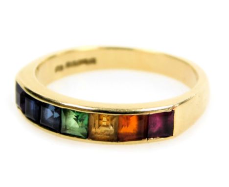 An 18ct gold and gem set rainbow ring, channel set with a ruby, fire opal, citrine, green garnet, light and dark blue sapphir