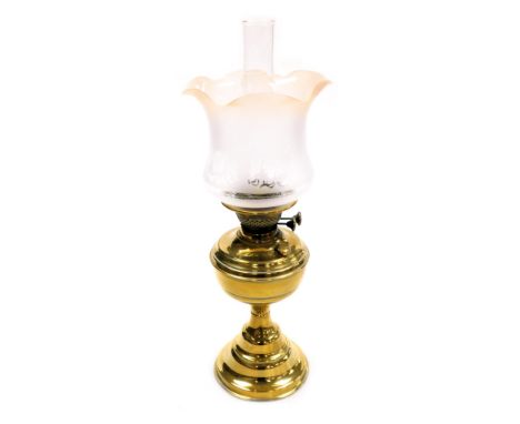An early 20thC duplex brass oil lamp, with a glass chimney and frosted frilled glass shade, 56cm high.