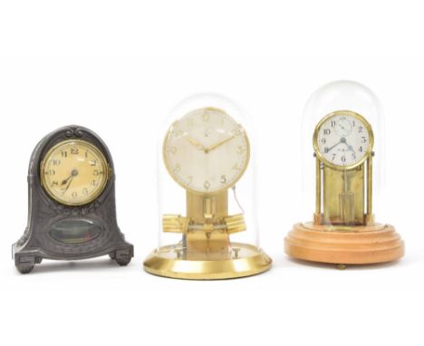 Unusual electric mantel clock, the 3.5" cream dial over an oval pendulum window and within a rounded arched flaring pewter ca