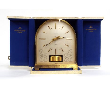 Unusual Jaeger LeCoultre Atmos clock, the 6.25" silvered arched dial within a brass bound burgundy coloured case, 8.25" high;