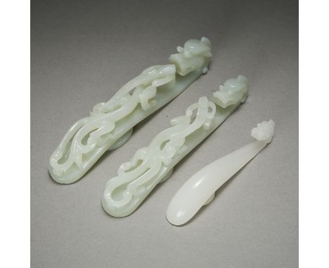 Group of three Chinese carved pale jade belt hooks, all caved with dragon heads. The two largest carved with pierced relief w