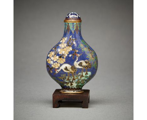 Chinese cloisonne snuff bottle with a wooden stand. The snuff bottle depicts colorful birds nestled amongst flowers and trees