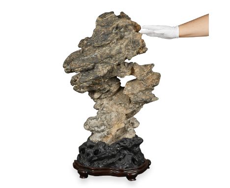 One Chinese scholar's rock or Lingbi stone on a rosewood and basalt stone stand, 19th century. In a dark grey color with a cr