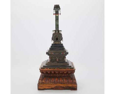 Tibetan Buddhist silver stupa inset with jade, coral, and turquoise. With an accompanying carved wooden stand. Stupas are pla