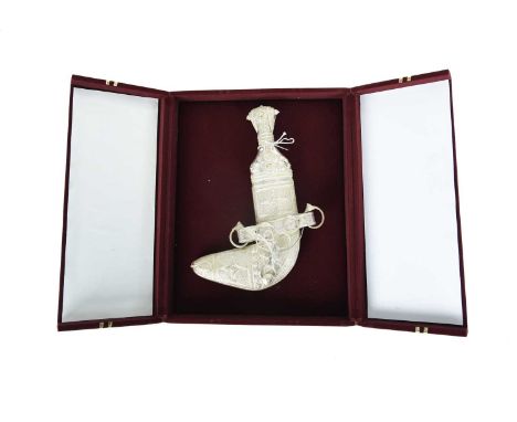 An Omani presentation or costume dagger (jambiya), curved blade 6 in., white metal hilt and scabbard with applied and repouss