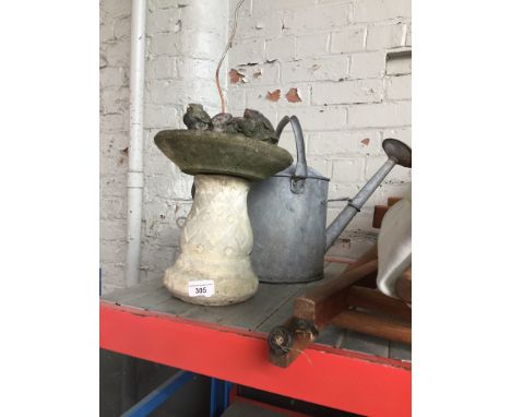 A small concrete bird bath, a concrete squirrel and a vintage watering can 