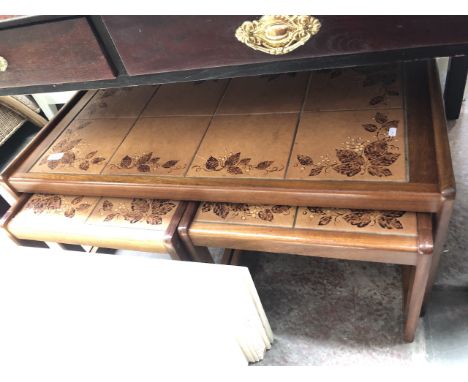 A nest of teak and tile top tables 