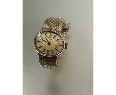A Lady's yellow metal 1960's Tissot manual wind wristwatch with oval gilt dial and baton hour markers on textured milanese li