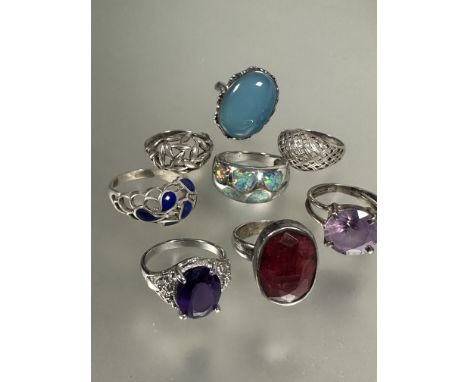 A collection of silver rings, two set, red dyed quartz, pale blue/green stone, two with lattice design, one set slithers of o