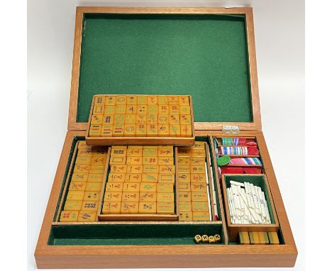 A boxed Mahjong set with amberine/plastic polymer counters, the interior with baize-lined compartments/trays (w- 44cm)
