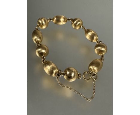 A yellow metal circular and oval bead chain link bracelet, each bead with textured finish, with ring clip fastening and safet