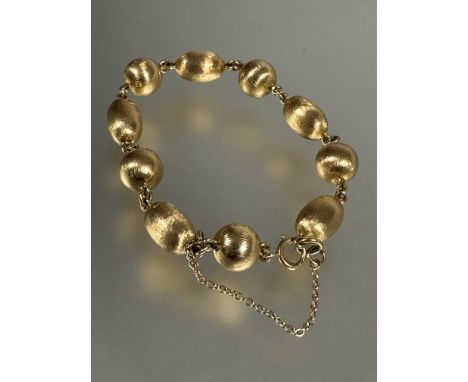 A yellow metal circular and oval bead chain link bracelet, each bead with textured finish, with ring clip fastening and safet