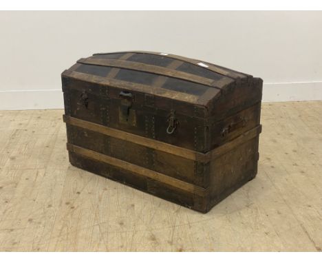 A late 19th century metal bound and leather covered dome top trunk, the hinged lid opening to a paper lined interior, lacking