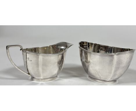 A Birmingham silver two piece part tea set comprising oval panel sided sugar basin, (H x 7.5cm x L 12cm) and milk jug, ( H x 