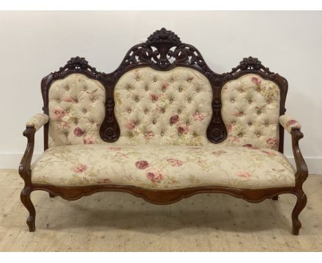 A Victorian walnut framed canope sofa, the floral carved crest rail over button back, open arms and seat upholstered in natur