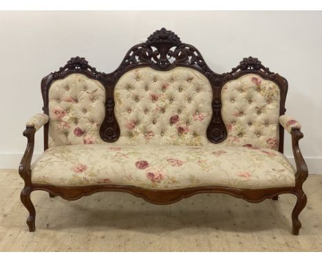 A Victorian walnut framed canope sofa, the floral carved crest rail over button back, open arms and seat upholstered in natur