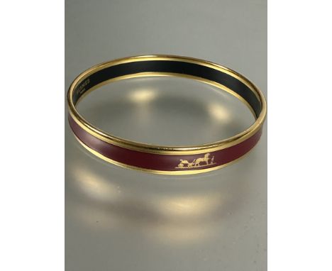 A gilt metal an dark rouge enamel stiff bangle with Groom a L'attante, made in Austria Hermes Paris, (H x 0.8cm x D x 6.5), p