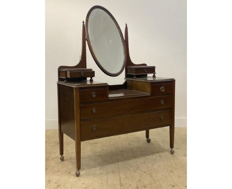 An Edwardian mahogany dressing chest, the bevelled oval mirror swivelling between two tapered posts, above two trinket drawer