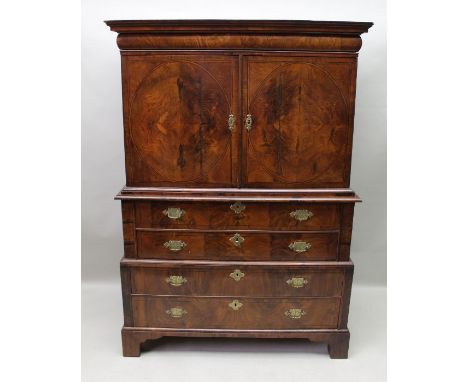 An early 19th century walnut chest on stand having concealed upper drawer over a pair of oval panel drawers revealing fitted 