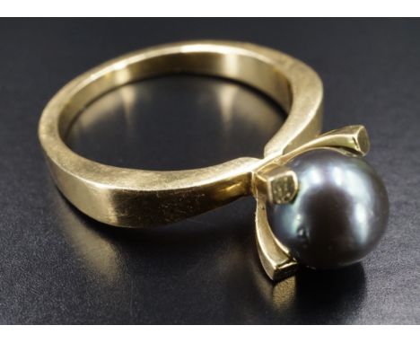 A modernist "pewter" pearl ring, the 7 mm pearl cradled by four tapering square-section claws on a shouldered 18 ct gold shan