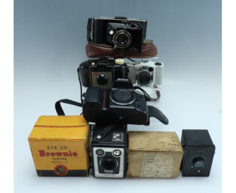 A Nikon F70 camera body together with a group of vintage cameras, including a Minox 35 AL, a boxed Kodak Brownie 127 and a Si