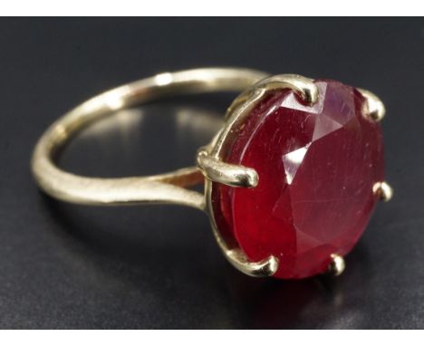 A modern 9 ct gold and ruby dress ring, having a 12 mm brilliant cut stone, basket-set between open tapering shoulders, Sheff