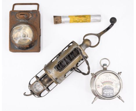 A vintage 12 vdc automotive inspection lamp, having a cable winder, a Pikco 'All in One' voltage tester, a tyre pressure gaug
