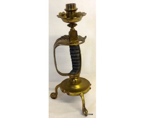 A Victorian trench art candlestick made from a sword basket hilt with three cavalry spurs as a stand 13 inches high overall