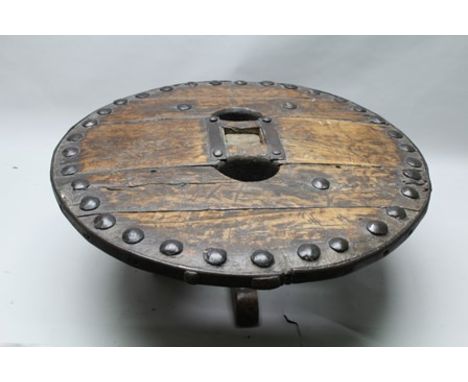 A NOVELTY CIRCULAR WOOD AND IRON COFFEE TABLE, fashioned from a Far Eastern cartwheel, having large decorative stud work and 