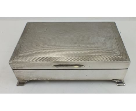 AN ART DECO DESIGN SILVER CIGARETTE BOX, hinged engine turned cover, cedar lined, raised on bracket feet, Birmingham 1962, 14