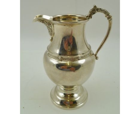 A MID-20TH CENTURY SILVER CREAM JUG of archaic baluster form, with Celtic band and knotwork decoration, cast dragon terminal 