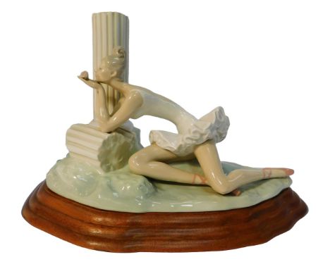 A Spanish porcelain figure group in the style of Lladro, modelled as a seated ballerina holding a rose beside a pillar, on an