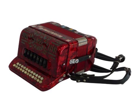 A Fantini button accordion, in red, in a canvas case.