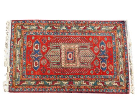 A Persian style carpet, with a central geometric latch hook medallion, surrounded by further multi-coloured medallions, on a 