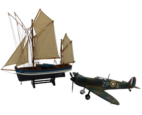 21stC Toys Inc model of a spitfire, 60cm wide, together with a painted wooden model of a fishing boat, with cloth sails, on a