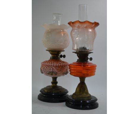An oil lamp on circular base, decorated with a tulip design around the bowl, 55cm high; together with another oil lamp,simila