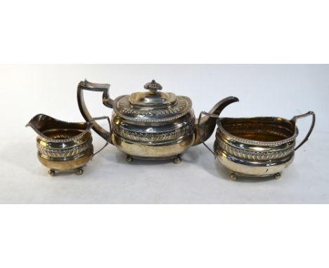 A George III Regency style three piece silver tea service with embossed decoration and gadrooned ruins, ivory insulators and 