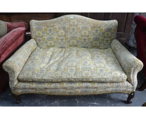 An upholstered two seat hump back sofa circa 1900, raised on short moulded cabriole legs to scroll feet, the frame stamped '1