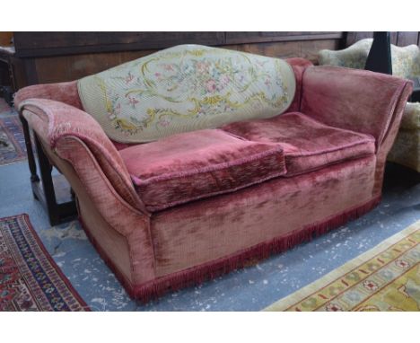 An old upholstered two seat arched back sofa having splayed arms and an ovoid needlepoint panel applied to the backrest, circ